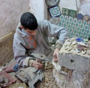 Breaking tile to use for mosaics. Ceramics factory in Fez, Morocco.